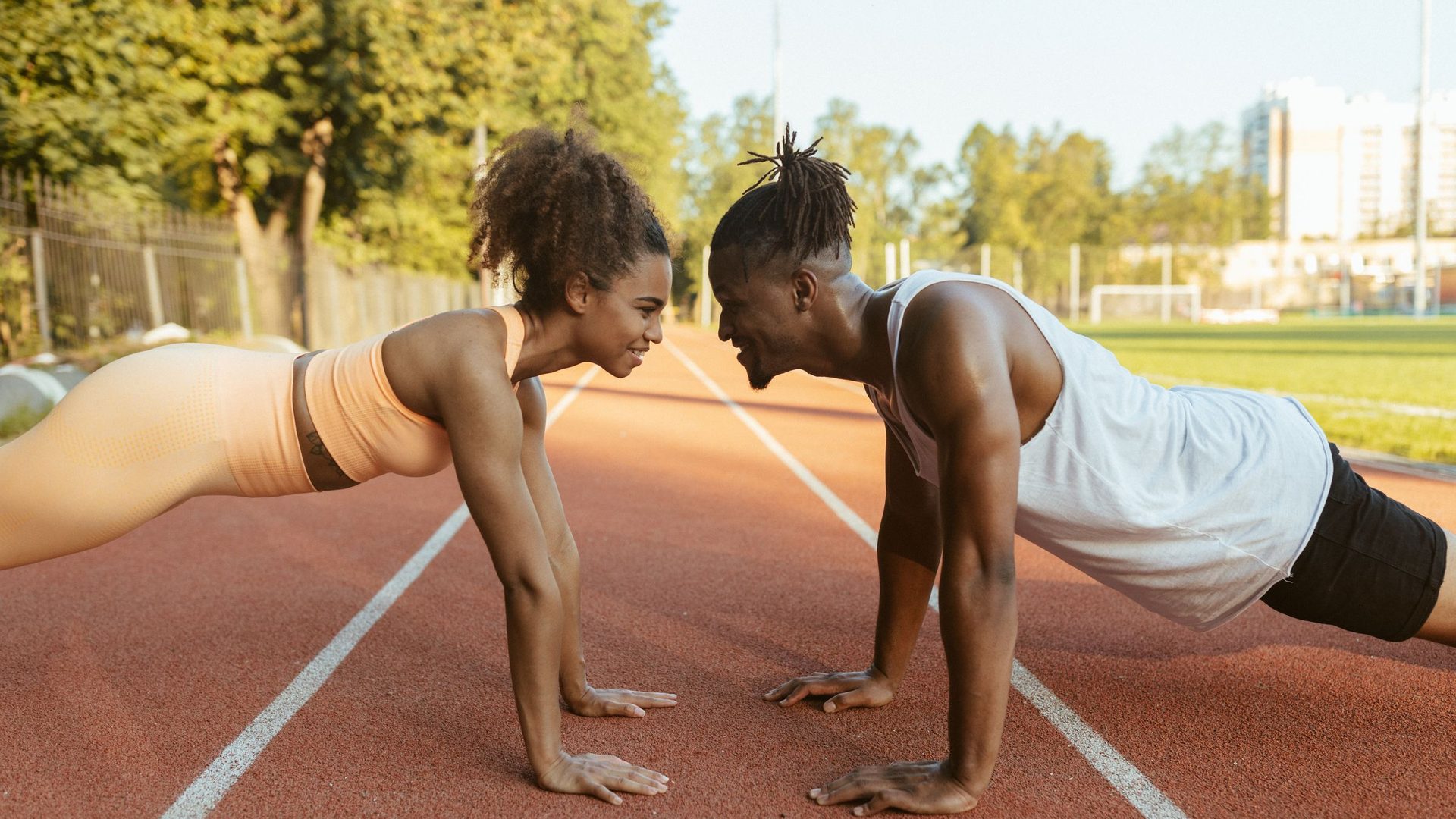 Rapaz e rapariga a fazer flexões numa pista de atletismo, em treino para as provas físicas da Academia Militar