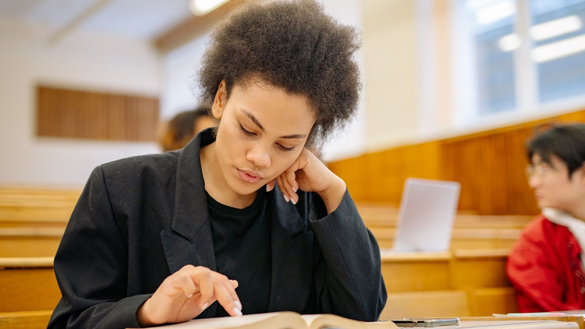 Estudante a ler um livro num anfiteatro universitário, a preparar-se para a admissão à UEM