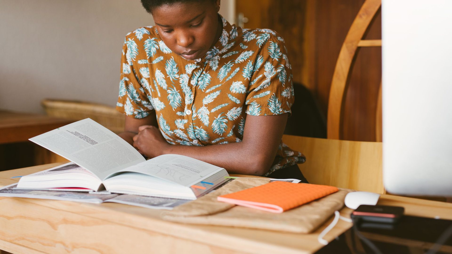 Estudante concentrada a ler um livro à secretária, a preparar-se para os exames de admissão 2027